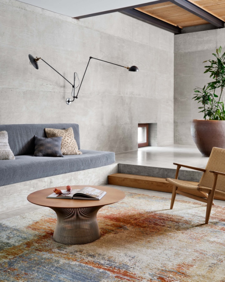 oversized rug softens mid-century living room with raw concrete 