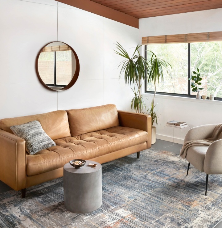  brown sofa in a white-walled living room with patterned rug