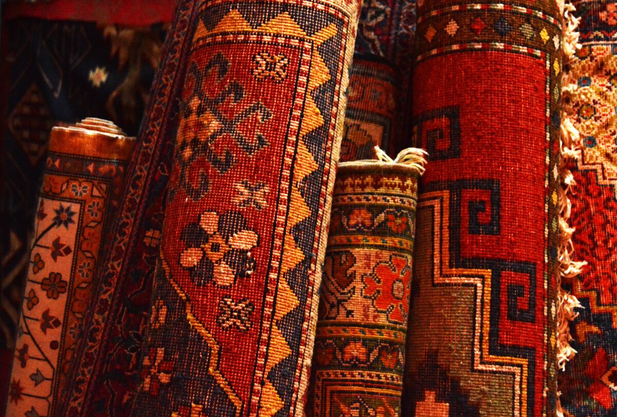 Warm-colored, rolled-up rugs with tribal and oriental prints on them.