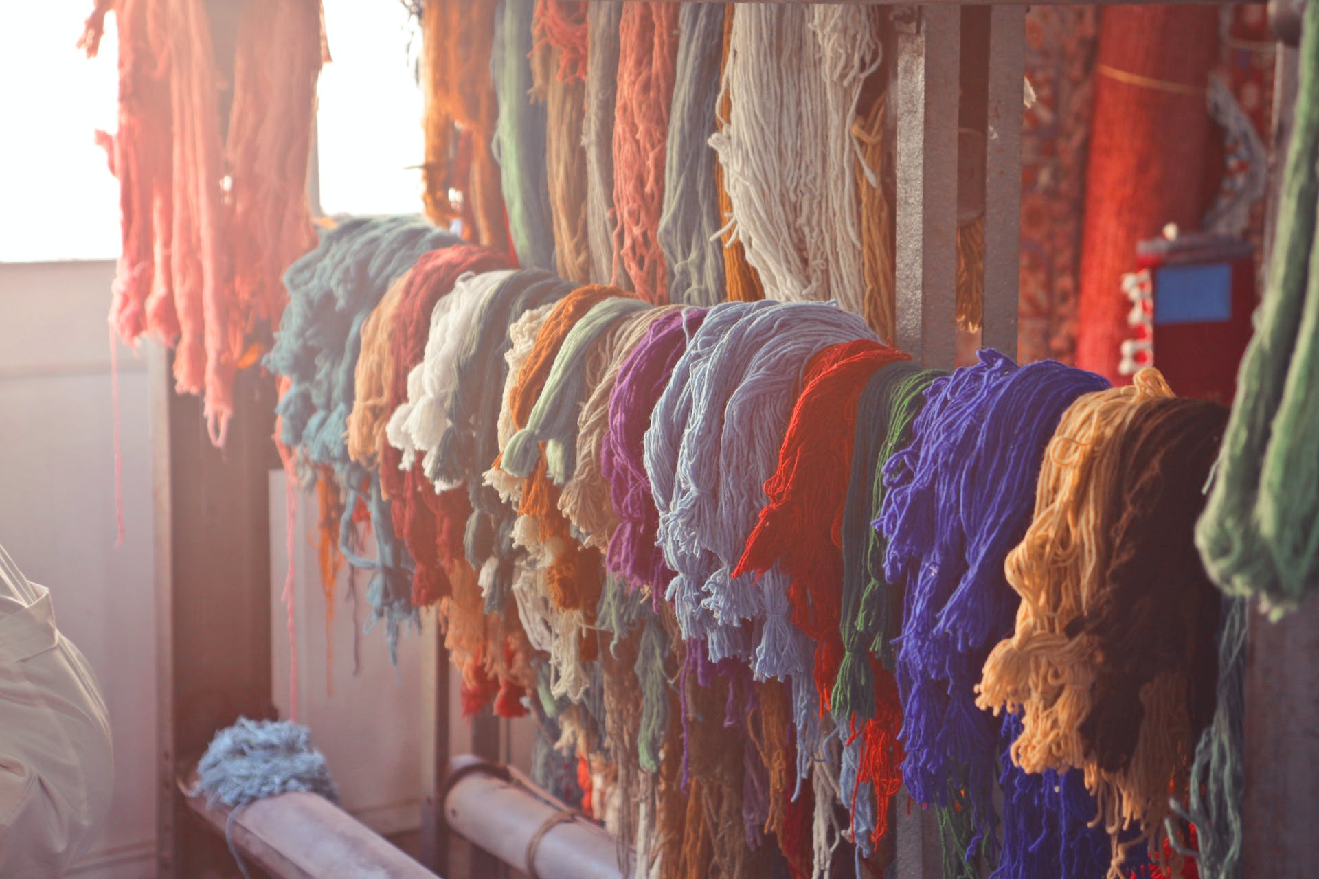 Colorful rug threads hanging on a rail